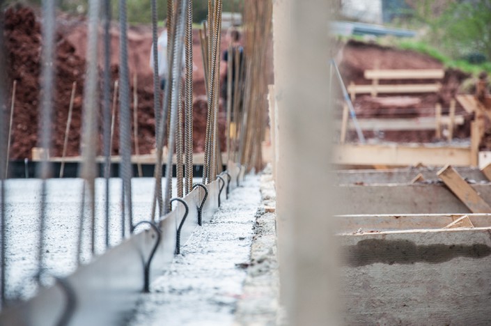 Reihen von aufgestellten Bewehrungen und Dichtungselementen auf vorbereiteter Betonplatte – Ausführung eines Weiße-Wanne-Systems bei MB Effizienzkeller