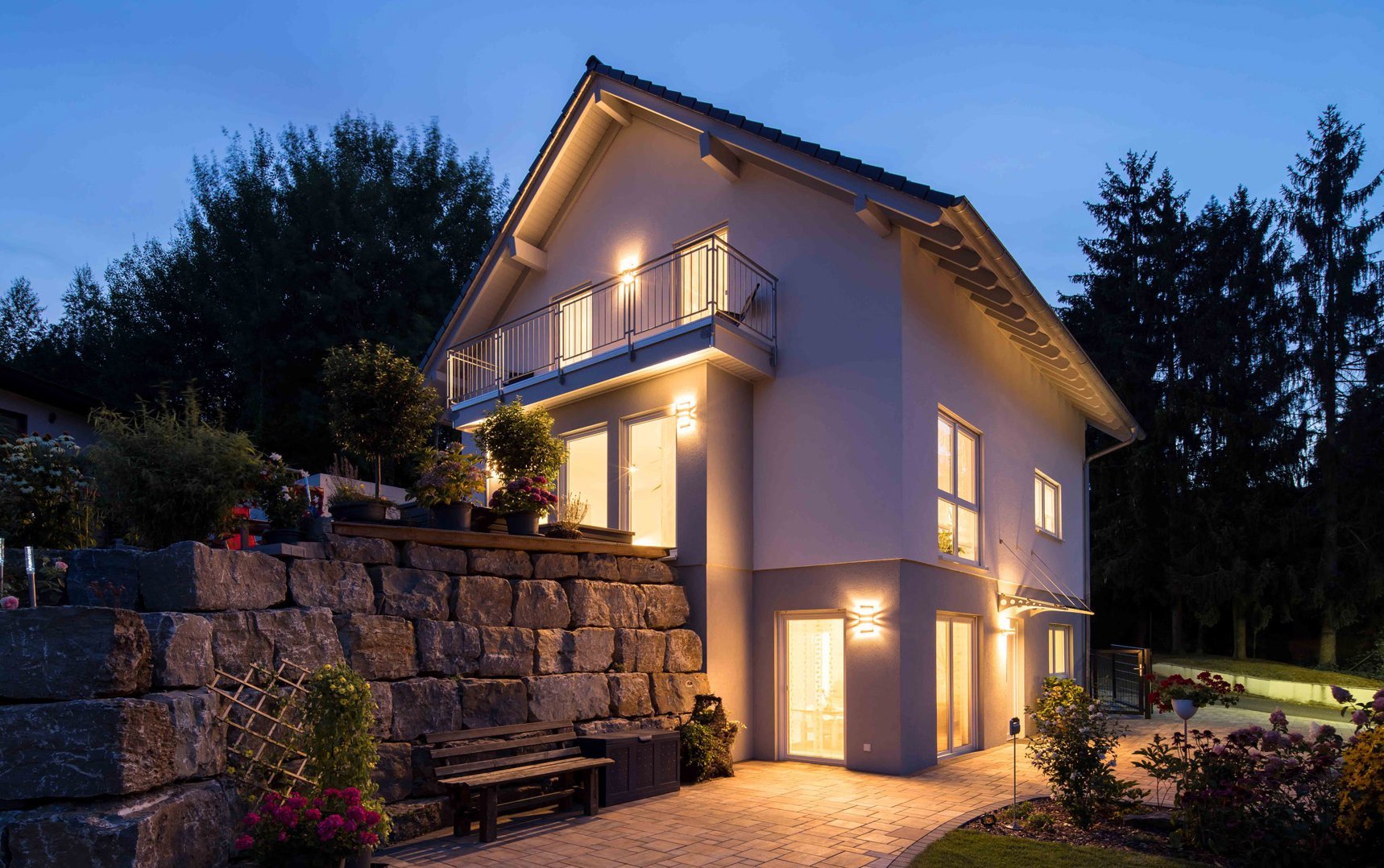 Zweigeschossiges Wohnhaus mit Satteldach und Fertigkeller von MB-Keller, terrassiert auf Hanglage mit Natursteinmauer
